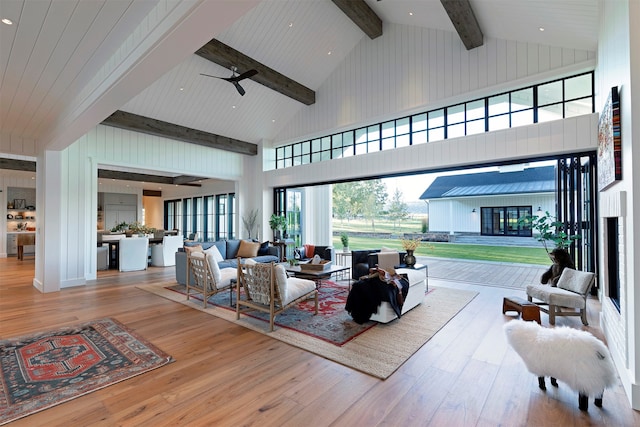 living room with a healthy amount of sunlight, wood-type flooring, beam ceiling, and high vaulted ceiling