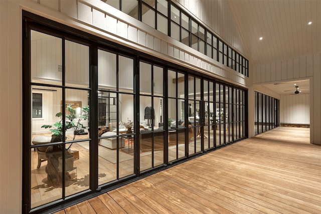 hall with light wood-type flooring and high vaulted ceiling