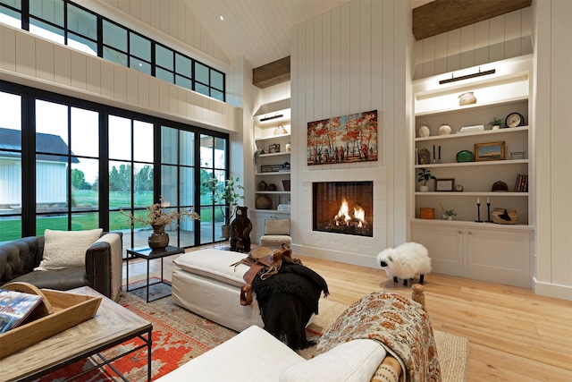 living room featuring high vaulted ceiling, a fireplace, built in features, wooden walls, and hardwood / wood-style floors