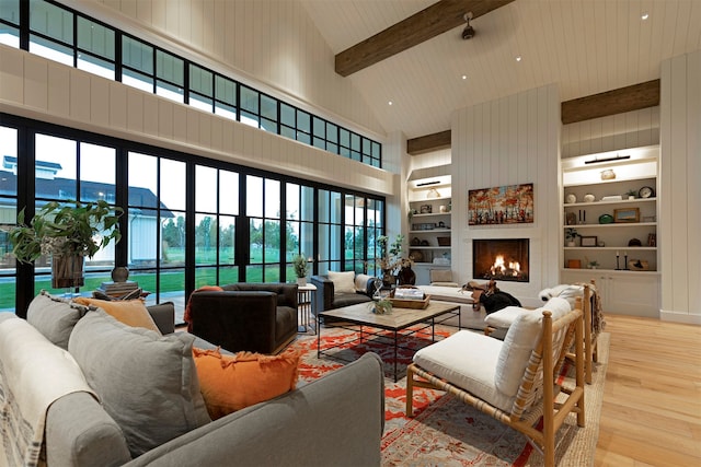 living room with beam ceiling, light hardwood / wood-style flooring, plenty of natural light, high vaulted ceiling, and a large fireplace