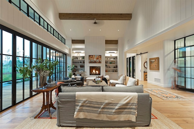 living room featuring beamed ceiling, a towering ceiling, a barn door, and hardwood / wood-style flooring