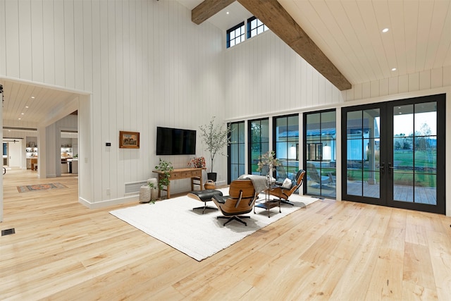 living room featuring light wood-type flooring, beam ceiling, and a wealth of natural light