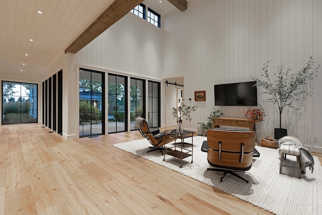 living room featuring light wood-type flooring, a barn door, beamed ceiling, and a high ceiling