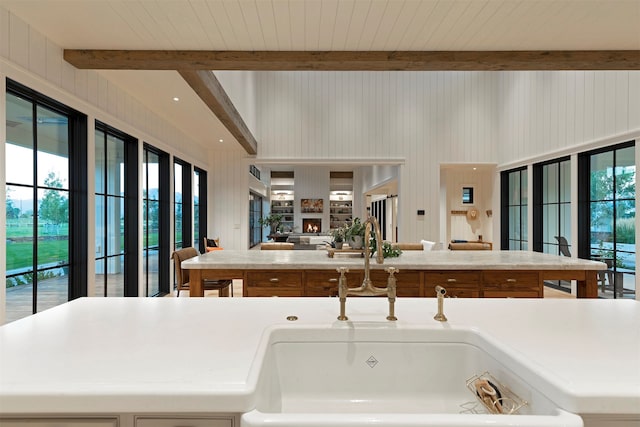 kitchen featuring sink, wooden walls, and beam ceiling