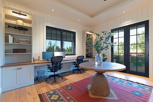 office space with built in desk, light wood-type flooring, built in features, and french doors