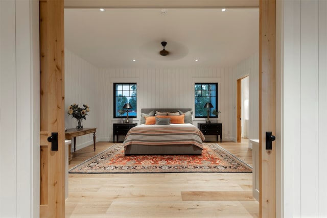 bedroom featuring wood walls and light hardwood / wood-style floors