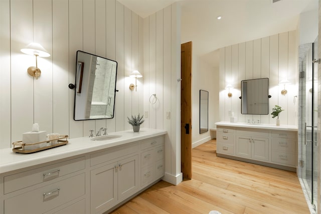 bathroom featuring an enclosed shower, wood walls, vanity, and hardwood / wood-style flooring