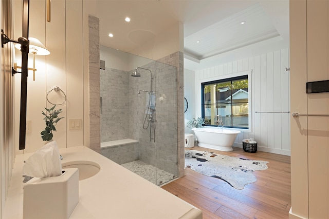 bathroom featuring shower with separate bathtub, a tray ceiling, wood-type flooring, and vanity