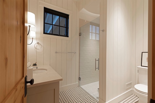 bathroom with tile patterned flooring, walk in shower, vanity, and toilet