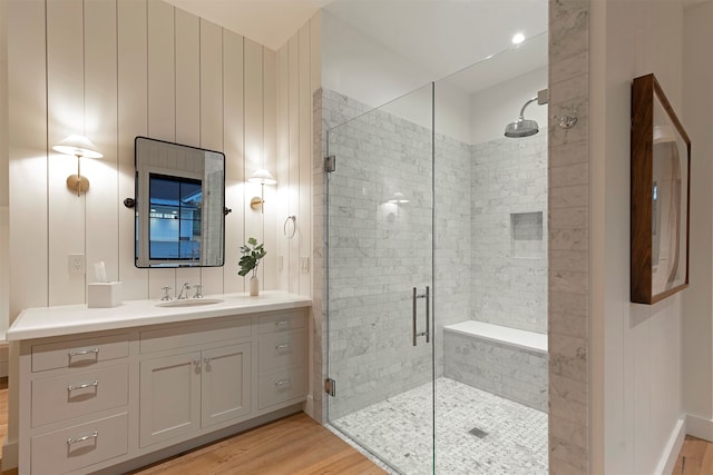 bathroom with wood-type flooring, vanity, and an enclosed shower