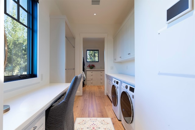 laundry area with cabinets, light hardwood / wood-style floors, and separate washer and dryer