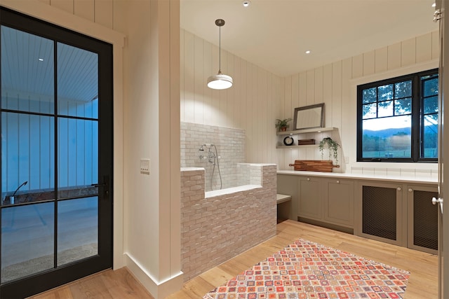 kitchen featuring light hardwood / wood-style floors, wood walls, gray cabinets, and decorative light fixtures