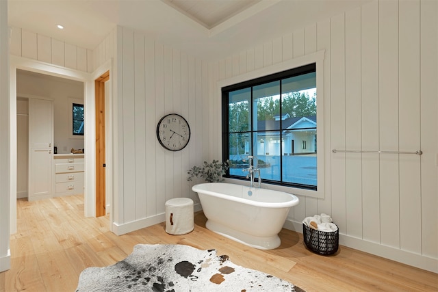 bathroom with wood walls, a washtub, and hardwood / wood-style floors