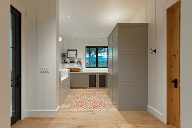 interior space with light hardwood / wood-style flooring, wood walls, and gray cabinetry