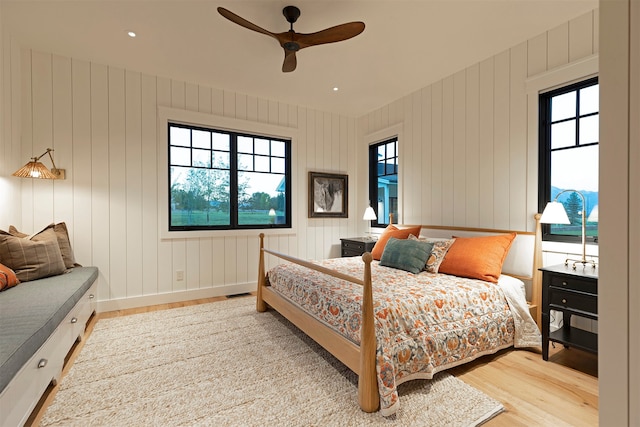 bedroom with wood walls, ceiling fan, and hardwood / wood-style flooring