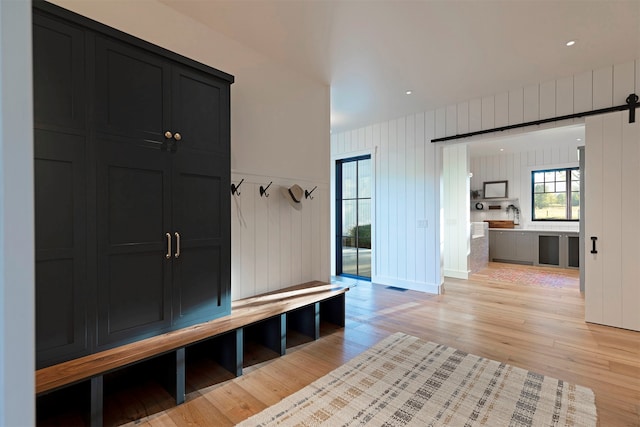 mudroom featuring a barn door, light hardwood / wood-style floors, and wood walls