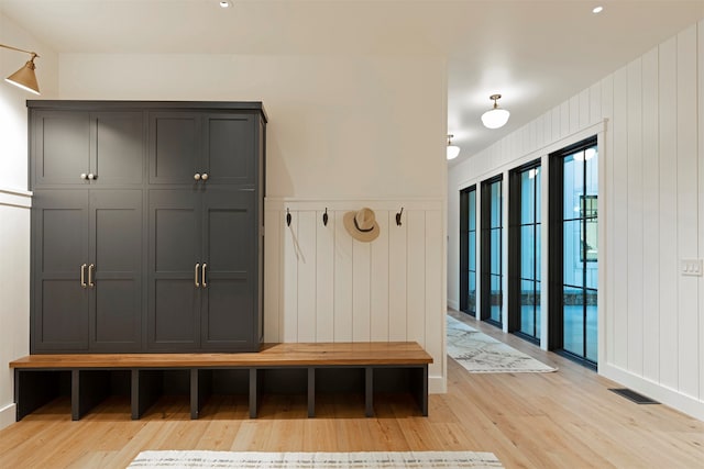 mudroom with light wood-type flooring and wood walls