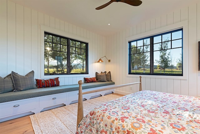 bedroom featuring ceiling fan, hardwood / wood-style flooring, and wooden walls