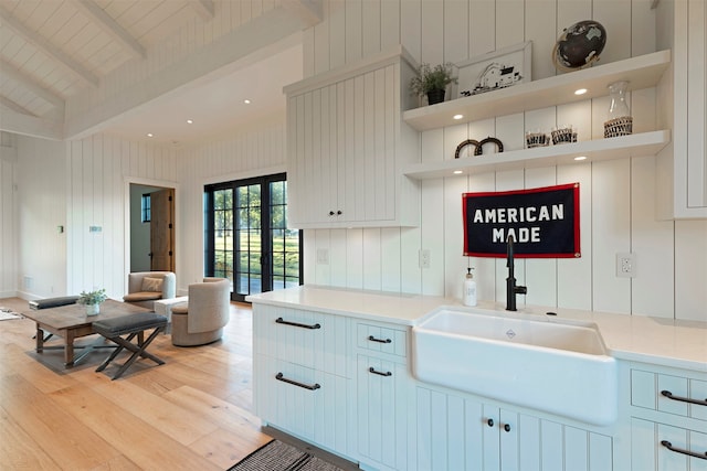 kitchen featuring beam ceiling, high vaulted ceiling, and white cabinets