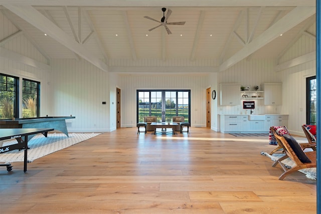 living room with light hardwood / wood-style floors, beam ceiling, and high vaulted ceiling