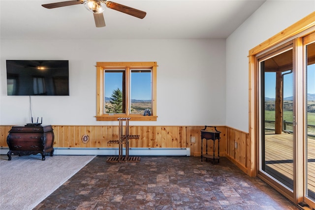 53 Skyview Ln, Townsend, MT 59644 - unfurnished living room featuring plenty of natural light, stone finish flooring, wainscoting, wood walls, and ceiling fan