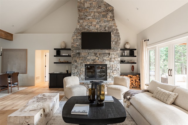 living room with a fireplace, high vaulted ceiling, and light wood-type flooring