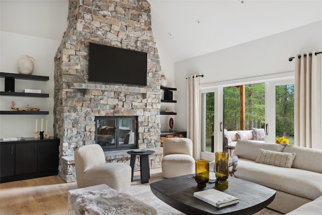 living room featuring high vaulted ceiling, a fireplace, and light hardwood / wood-style flooring