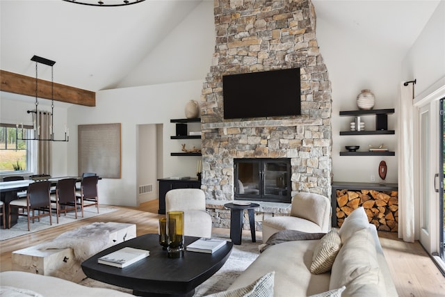 living room with an inviting chandelier, a fireplace, high vaulted ceiling, and light hardwood / wood-style flooring