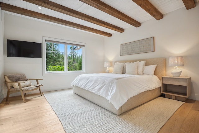 bedroom with light hardwood / wood-style floors and beam ceiling