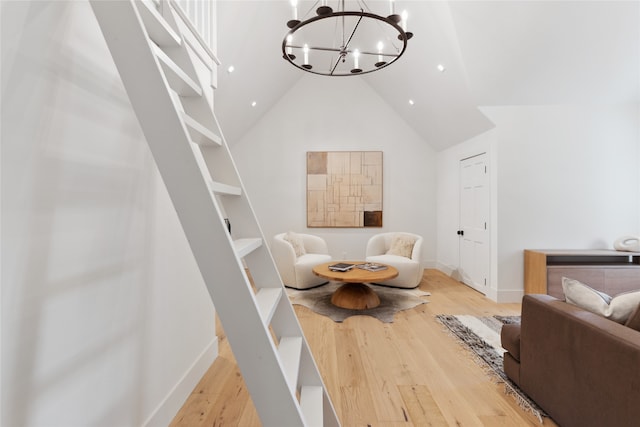 living room with an inviting chandelier, light wood-type flooring, and high vaulted ceiling