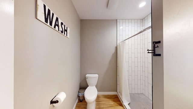 bathroom featuring tiled shower and toilet