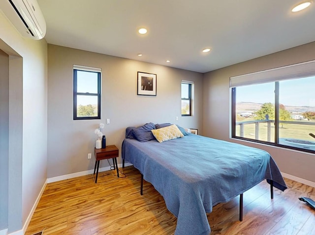 bedroom with light wood-type flooring and a wall mounted AC