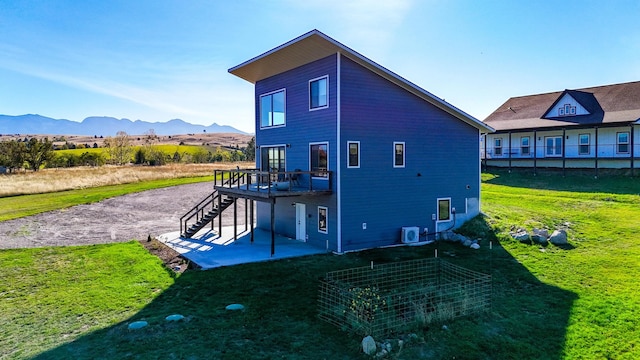 rear view of property featuring a lawn, central AC unit, a mountain view, and a patio area