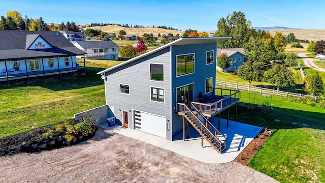 rear view of property with a lawn, a mountain view, and a garage