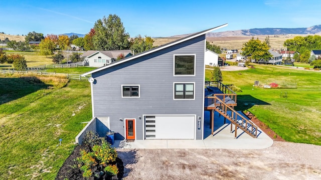 view of side of property featuring a mountain view, a garage, and a lawn