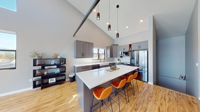 kitchen with a breakfast bar area, hanging light fixtures, a kitchen island, high vaulted ceiling, and stainless steel appliances