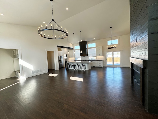 unfurnished living room featuring a towering ceiling, dark hardwood / wood-style floors, and sink