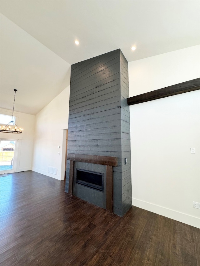 unfurnished living room featuring high vaulted ceiling, a large fireplace, dark wood-type flooring, and a notable chandelier