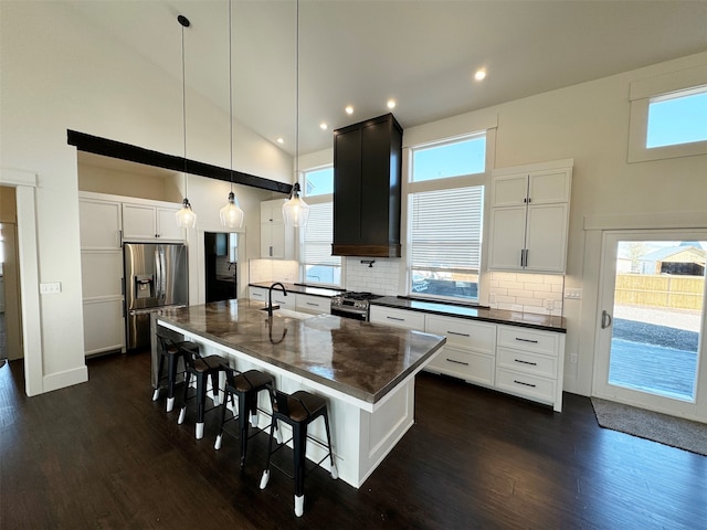 kitchen featuring a center island with sink, appliances with stainless steel finishes, dark wood-type flooring, and a healthy amount of sunlight