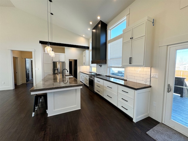 kitchen with high vaulted ceiling, stainless steel appliances, white cabinets, and decorative light fixtures