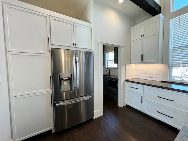 kitchen with stainless steel refrigerator with ice dispenser, a wealth of natural light, dark hardwood / wood-style floors, and white cabinets