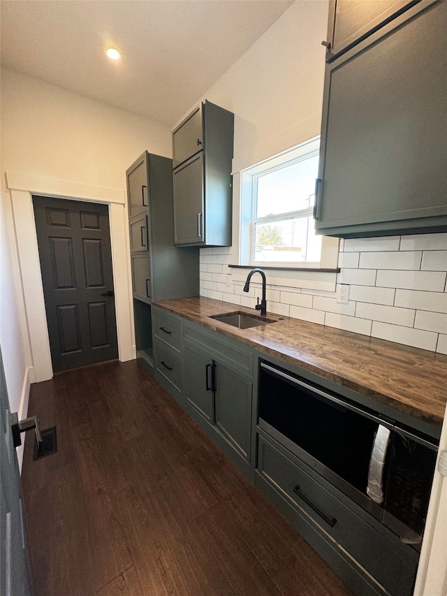 kitchen with gray cabinets, dark wood-type flooring, sink, butcher block counters, and decorative backsplash