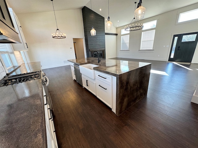 kitchen featuring a center island with sink, white cabinetry, pendant lighting, and high vaulted ceiling