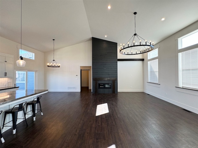 unfurnished living room featuring high vaulted ceiling and dark wood-type flooring