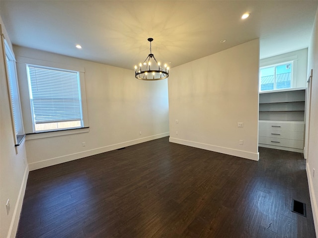 empty room with an inviting chandelier and dark hardwood / wood-style flooring