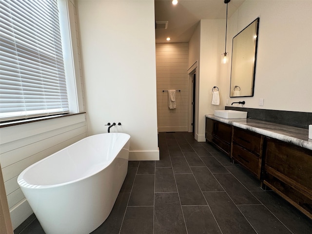 bathroom with tile patterned flooring, a bath, and vanity