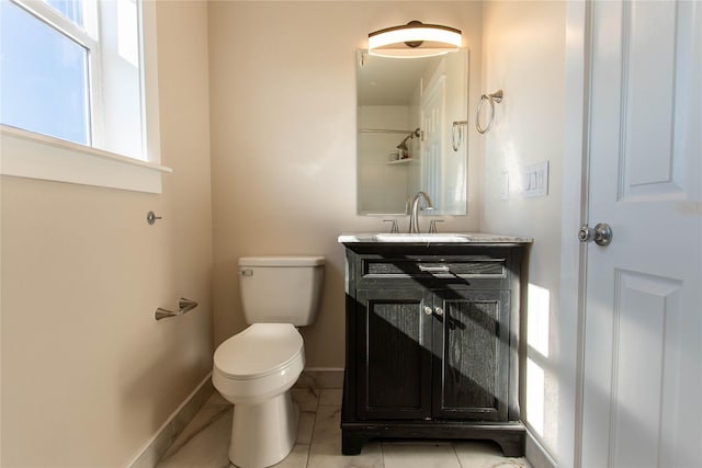 bathroom with toilet, vanity, and baseboards