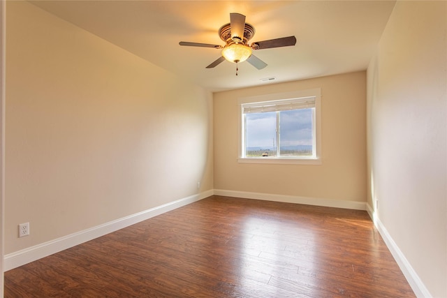 empty room featuring dark wood-style flooring, visible vents, ceiling fan, and baseboards