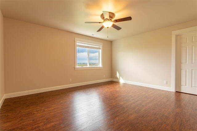 empty room with dark wood-type flooring, baseboards, and a ceiling fan