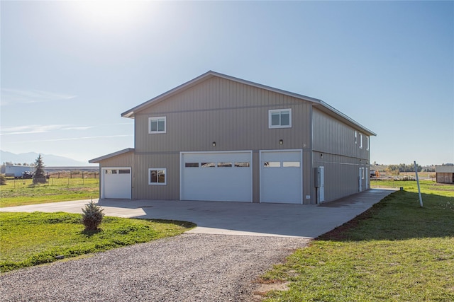 view of side of property with a garage, driveway, a mountain view, and a lawn